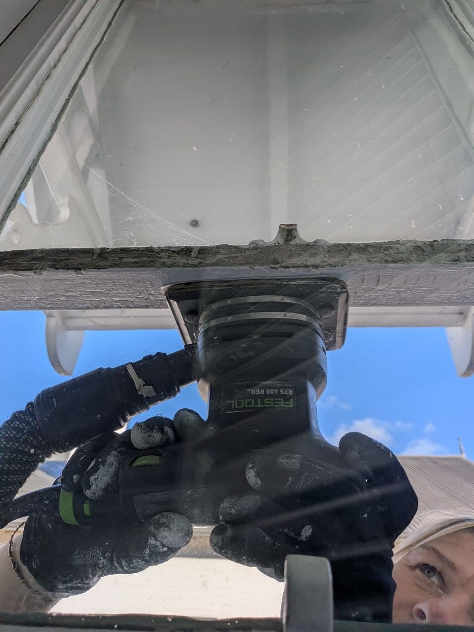Sanding a window frame with an orbital sander